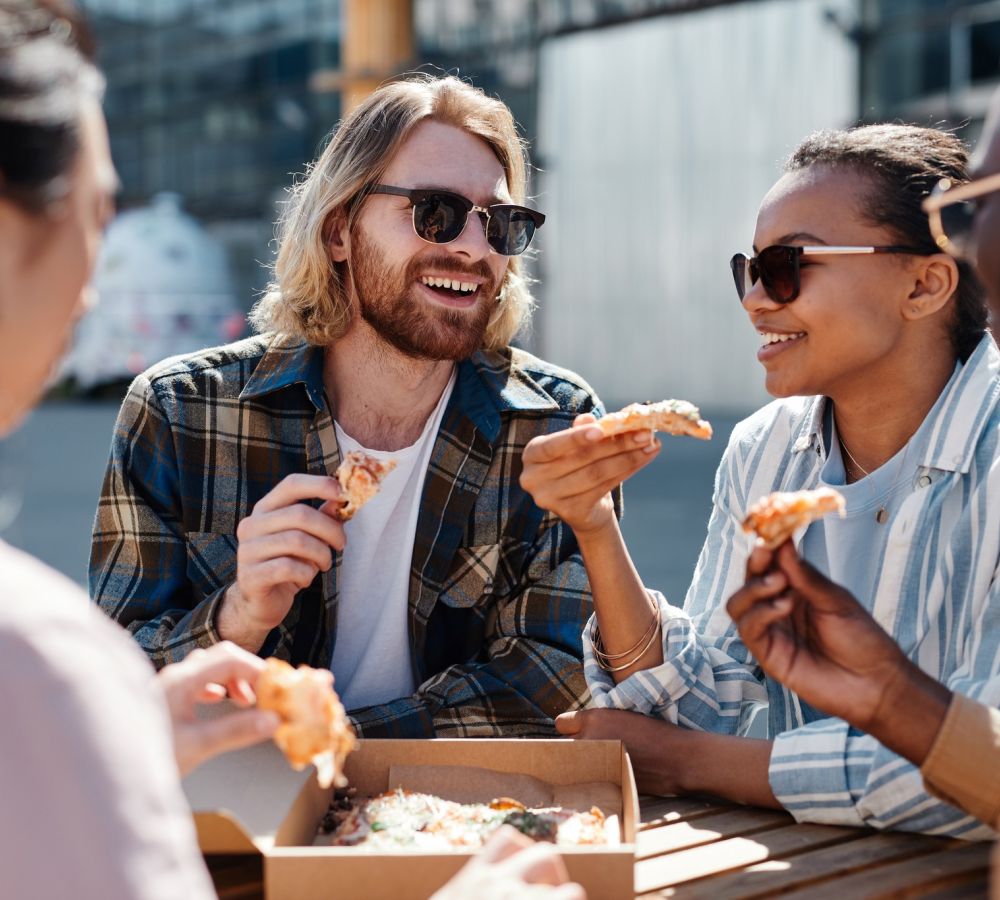 Alta Stone at the Gateway residents enjoying pizza together outside while wearing sunglasses